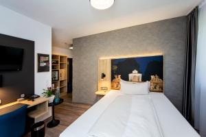 a bedroom with a large white bed and a tv at Arcus Hotel München Messe in Feldkirchen +91 photos