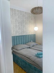 a bed with a blue headboard in a room at Apartamenty na skraju lasu in Ustka