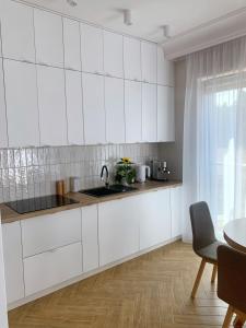 a white kitchen with white cabinets and a table at Apartamenty na skraju lasu in Ustka