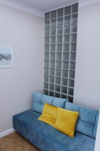 a blue couch with a yellow pillow in a room at Apartamenty na skraju lasu in Ustka