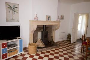 a living room with a fireplace and a tv at Gîte Aux Tuileries in Noaillan