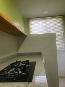 a kitchen with a black stove top in a room at LOFT aconchegante no Centro de Macaé, Wifi, Ar condicionado e Cozinha completa in Macaé