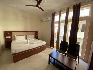 a bedroom with a bed and a chair and a table at Hotel The Shivaay - Delight Inn Rishikesh in Rishīkesh