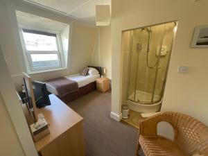 a bathroom with a bed and a shower and a desk at Alexanders in Hastings