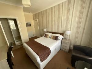 Habitación de hotel con cama y silla en Alexanders en Hastings
