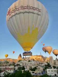 um monte de balões de ar quente voando sobre uma cidade em Aren Cave Hotel And Art Gallery em Goreme