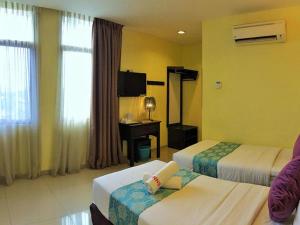 a hotel room with two beds and a desk at Sun Inns Dmind Seri Kembangan in Seri Kembangan