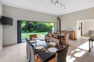 a dining room with a table and chairs and a large window at De Akker Guest House in Bloemfontein