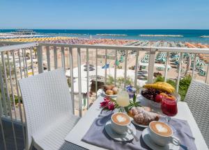 uma mesa com comida e bebidas numa varanda com praia em Strand Hotel em Gabicce Mare