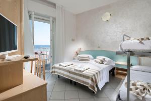 1 dormitorio con 2 camas, TV y balcón en Strand Hotel, en Gabicce Mare