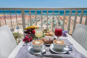 una mesa con dos tazas de café y una cesta de comida en Strand Hotel, en Gabicce Mare