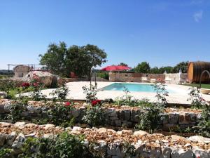 a swimming pool with flowers and a stone wall at Tenuta Colavecchio B&B in Putignano