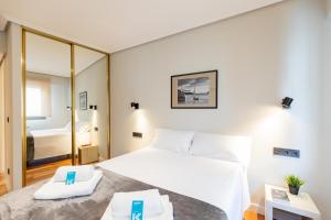 1 dormitorio con 1 cama blanca grande y espejo en Agirre - BasKey rentals, en Lekeitio