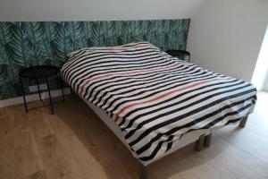 ein Bett mit einer schwarz-weißen gestreiften Decke in der Unterkunft Gite de Kerampif in Pluherlin