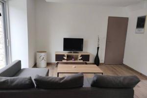 ein Wohnzimmer mit einem Sofa und einem Flachbild-TV in der Unterkunft Gite de Kerampif in Pluherlin