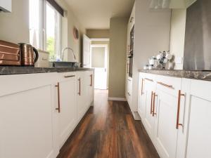 a kitchen with white cabinets and a wooden floor at 1 Lytham Terrace in Carnforth
