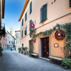 una strada con un edificio con un orologio sopra di Albergo Il Giglio a Montalcino