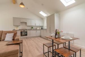 a kitchen and living room with a table and a couch at Lily - Luxury Barn Accommodation in the Cotswolds in Cheltenham