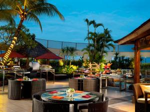 a restaurant with tables and chairs and palm trees at Hotel Ciputra Jakarta in Jakarta