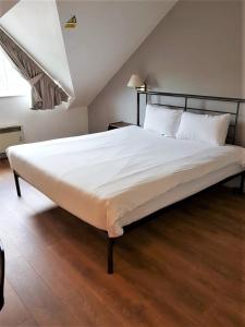 a bedroom with a large bed with white sheets at 247Hotel.com in Oldham