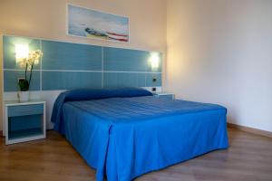 sypialnia z niebieskim łóżkiem z niebieską narzutą w obiekcie Residenza Del Mare w mieście Sant'Isidoro