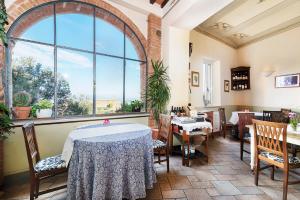 een restaurant met tafels en stoelen en een groot raam bij Albergo Il Giglio in Montalcino