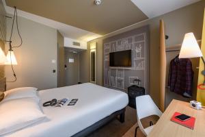 a hotel room with a bed and a table and a tv at ibis Regensburg Zentrum in Regensburg