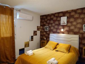 a bedroom with a yellow bed with towels on it at Astrotel Romorantin-Lanthenay Soirée étape in Romorantin