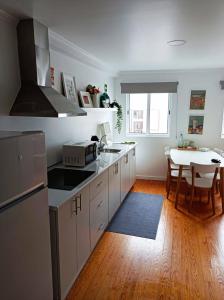 a kitchen with white cabinets and a table with a dining room at City Center House in Ponta Delgada