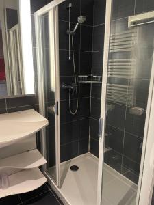 La salle de bains est pourvue d'une douche avec une porte en verre. dans l'établissement City'O apparthotel, à Caen