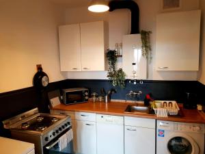 a kitchen with white cabinets and a sink and a stove at Design-Apartment für 4 mit Küche Nahe der City in Hannover