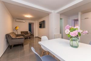 een woonkamer met een witte tafel en bloemen in een vaas bij Apartment Jakov with pool in Zadar