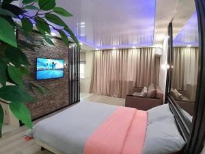 a bedroom with a bed and a tv on a wall at Apartment on Potanina 16 in Ustʼ-Kamenogorsk