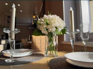 a table with plates and a vase of flowers on it at Apartment on Potanina 16 in Ustʼ-Kamenogorsk +1 photo