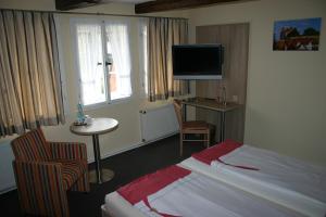 um quarto de hotel com uma cama e uma mesa e uma televisão em Hotel Zum Schloss em Quedlinburg