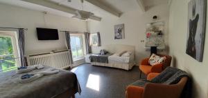 a room with two beds and a chair and a tv at B&B Blauwestadhoeve in Midwolda
