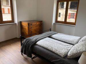 een slaapkamer met een bed, een dressoir en 2 ramen bij Appartamento Trentino I in Comano