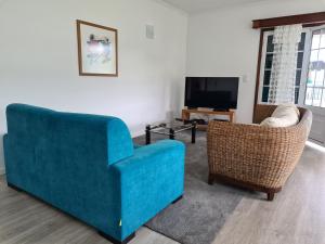 1 sofá azul y 2 sillas en la sala de estar. en Casa da Adega, en Ribeira Chã