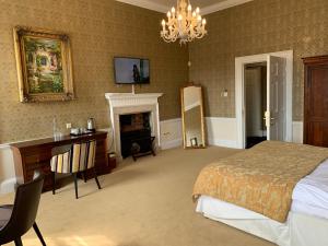 a bedroom with a bed and a desk and a fireplace at Colwick Hall Hotel in Nottingham