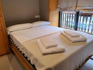 1 cama con 2 toallas y ventana en VIELHA XVI en Vielha