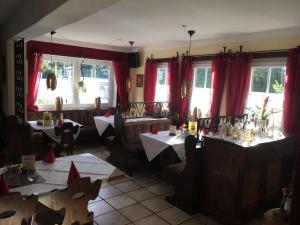 a restaurant with tables and chairs and red curtains at Zum weißen Ross in Nidda