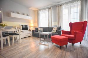 ein Wohnzimmer mit einem Sofa und einem roten Stuhl in der Unterkunft Apartamenty na Wyspie - Villa Park - Parking in Świnoujście