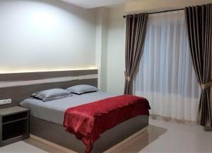 a bedroom with a bed with a red blanket and a window at Hotel Grand Sigma in Lahat