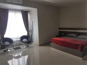um quarto com uma cama, 2 cadeiras e uma janela em Hotel Grand Sigma em Lahat