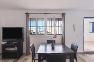 una sala da pranzo con tavolo, sedie e TV di Apartamento en la playa con Wifi a Tarifa