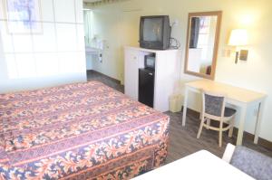 a hotel room with a bed and a table and a tv at Scottish Inn and Suites NRG Park/Texas Medical Center - Houston in Houston