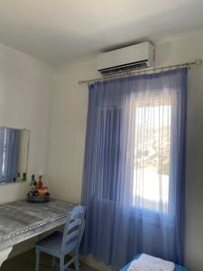 een kamer met een raam met een blauw gordijn bij Sikinos Best View in Alopronia