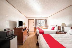 una camera d'albergo con due letti e una televisione di OYO Hotel Windmill Branson a Branson