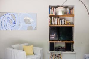 a living room with a white chair and a book shelf at Athenian Yard Near Acropolis in Athens