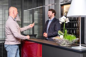 zwei Männer stehen neben einem Tisch in einem Zimmer in der Unterkunft Hotel Restaurant Esser in Wegberg